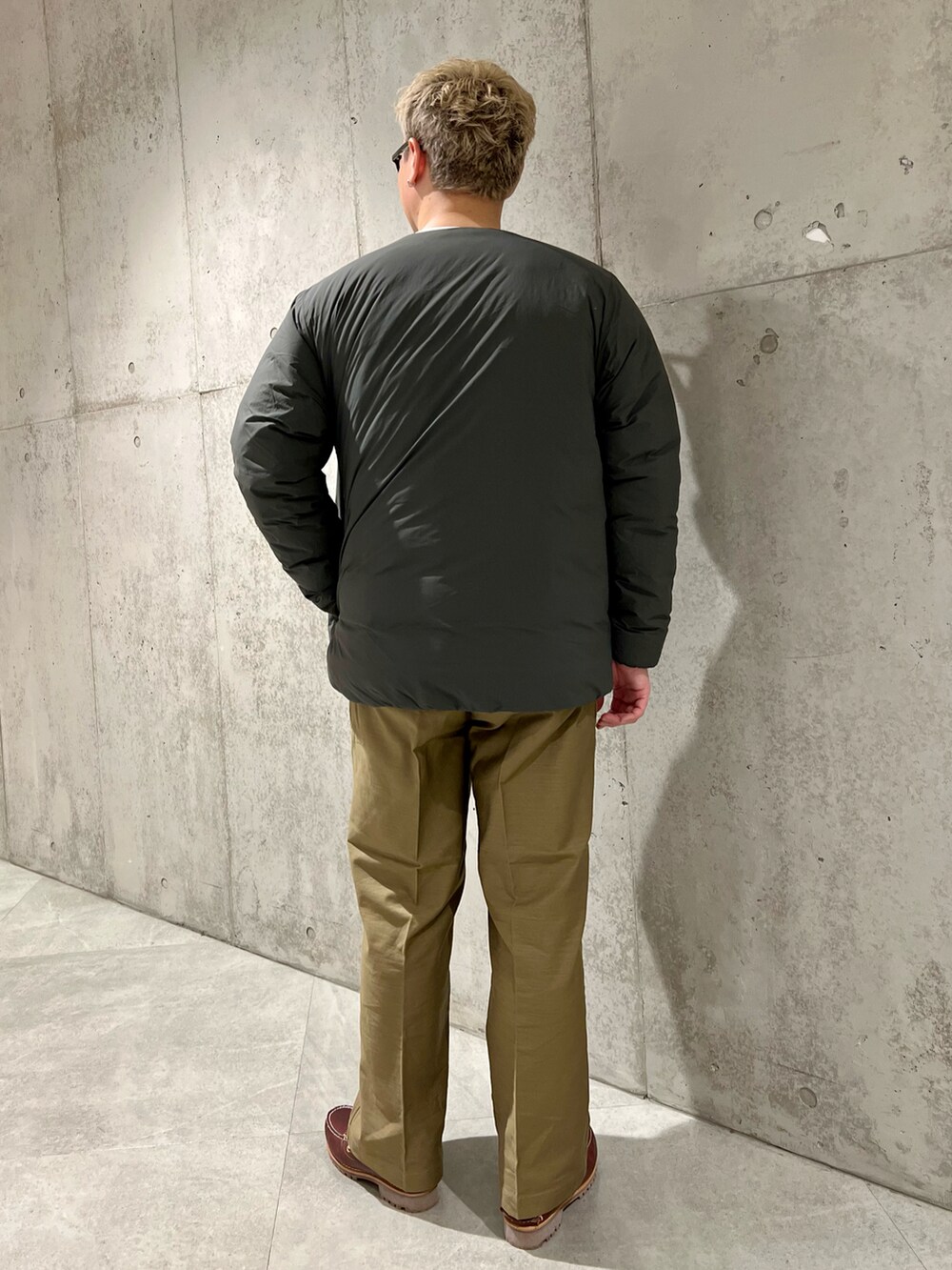 グレー系のダウンジャケット/コート、グリーン系のその他パンツ、レッド系のモカシン/デッキシューズを着用したメンズの秋コーディネートの3枚目の写真