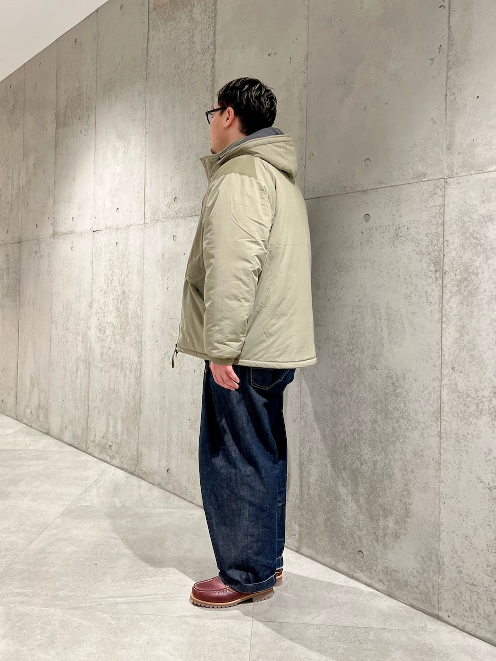 グリーン系のブルゾン、レッド系のモカシン/デッキシューズ、イエロー系のカーディガン/ボレロを着用したメンズの冬コーディネートの2枚目の写真