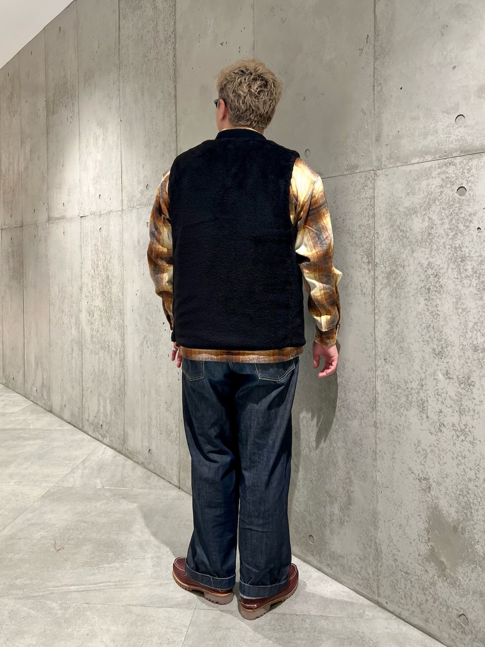 ブラック系のその他アウター、ブルー系のデニムパンツ、レッド系のモカシン/デッキシューズを着用したメンズの秋コーディネートの3枚目の写真