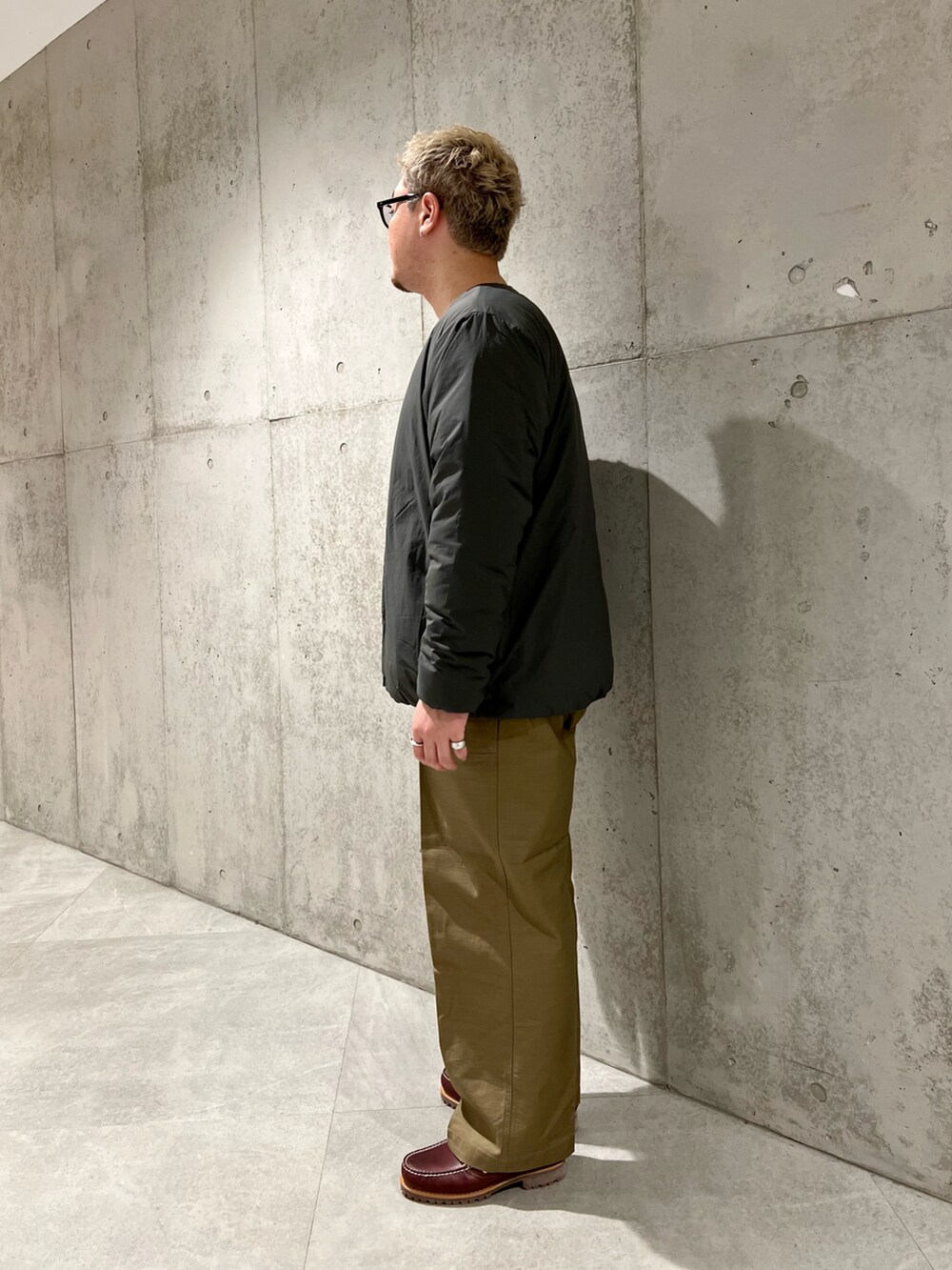 グレー系のダウンジャケット/コート、グリーン系のその他パンツ、レッド系のモカシン/デッキシューズを着用したメンズの秋コーディネートの2枚目の写真