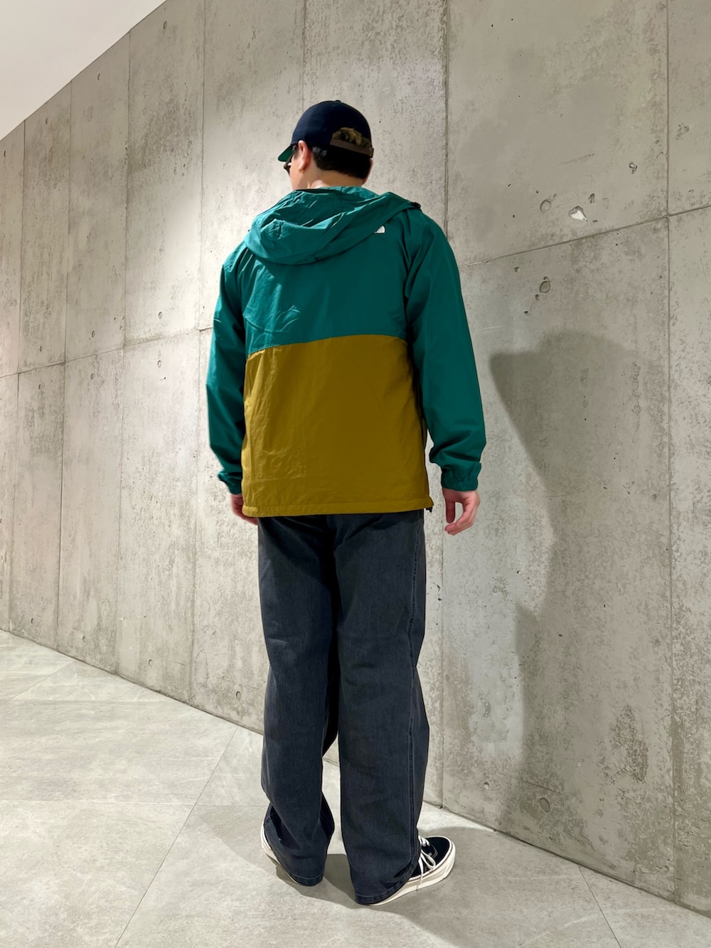 グリーン系のナイロンジャケット、ブラック系のデニムパンツ、ブラック系のスニーカーを着用したメンズの秋コーディネートの3枚目の写真