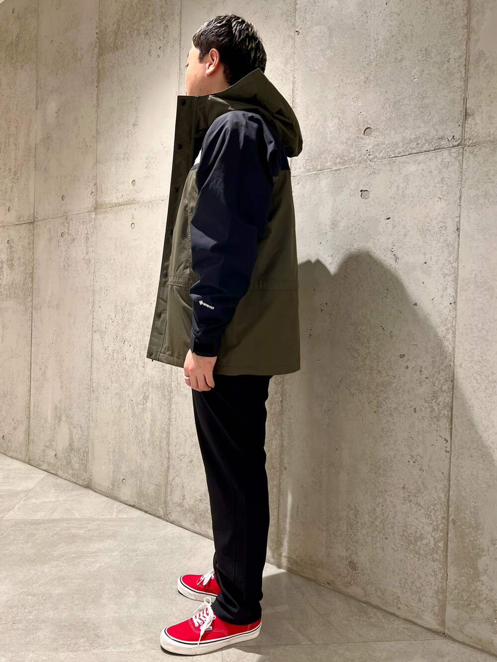 グリーン系のナイロンジャケット、ブラック系のTシャツ/カットソー、ブラック系のその他パンツを着用したメンズの春コーディネートの5枚目の写真