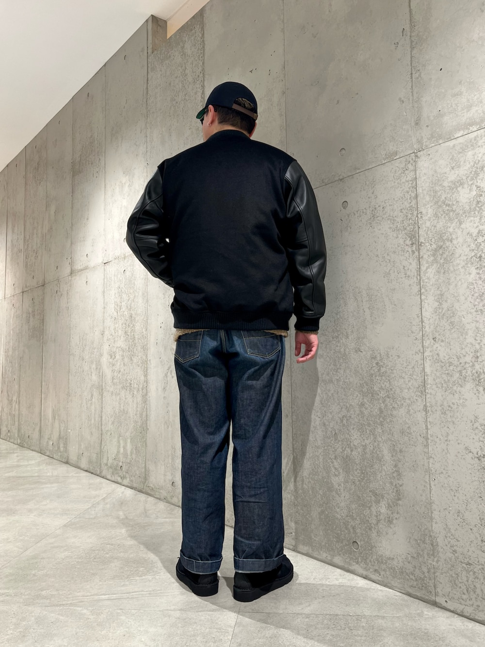 ブラック系のブルゾン、ブラック系のブーツ、グリーン系のニット/セーターを着用したメンズの冬コーディネートの3枚目の写真