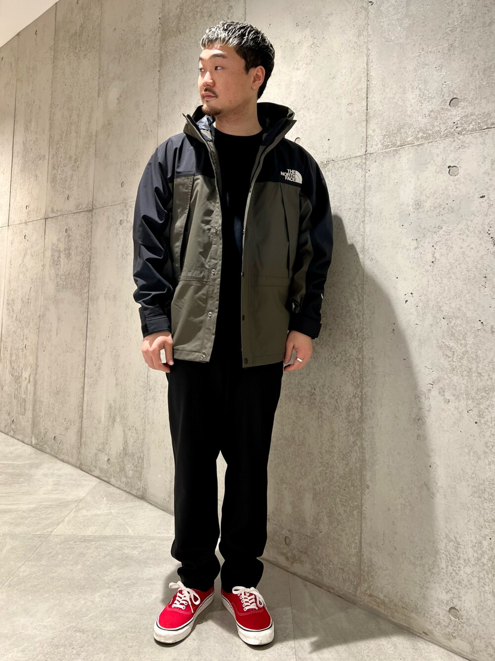 グリーン系のナイロンジャケット、ブラック系のTシャツ/カットソー、ブラック系のその他パンツを着用したメンズの春コーディネートの2枚目の写真