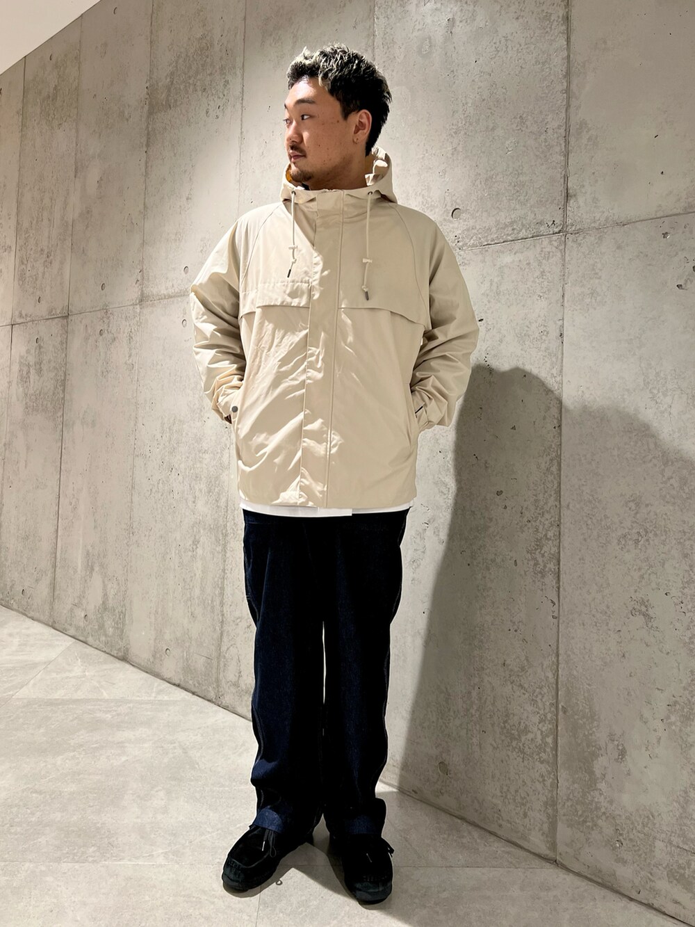 ホワイト系のマウンテンパーカー、グリーン系のTシャツ/カットソー、ブラック系のブーツを着用したメンズの春コーディネートの2枚目の写真