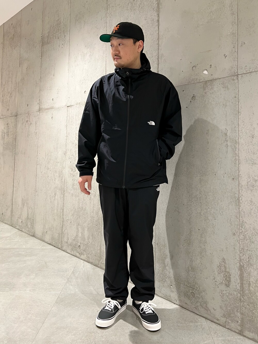 ブラック系のマウンテンパーカー、ホワイト系のTシャツ/カットソー、ブラック系のスニーカーを着用したメンズの春コーディネートの2枚目の写真