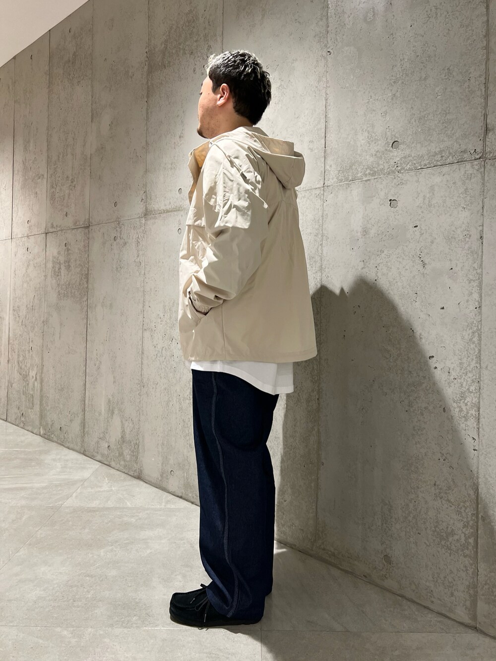 ホワイト系のマウンテンパーカー、グリーン系のTシャツ/カットソー、ブラック系のブーツを着用したメンズの春コーディネートの3枚目の写真