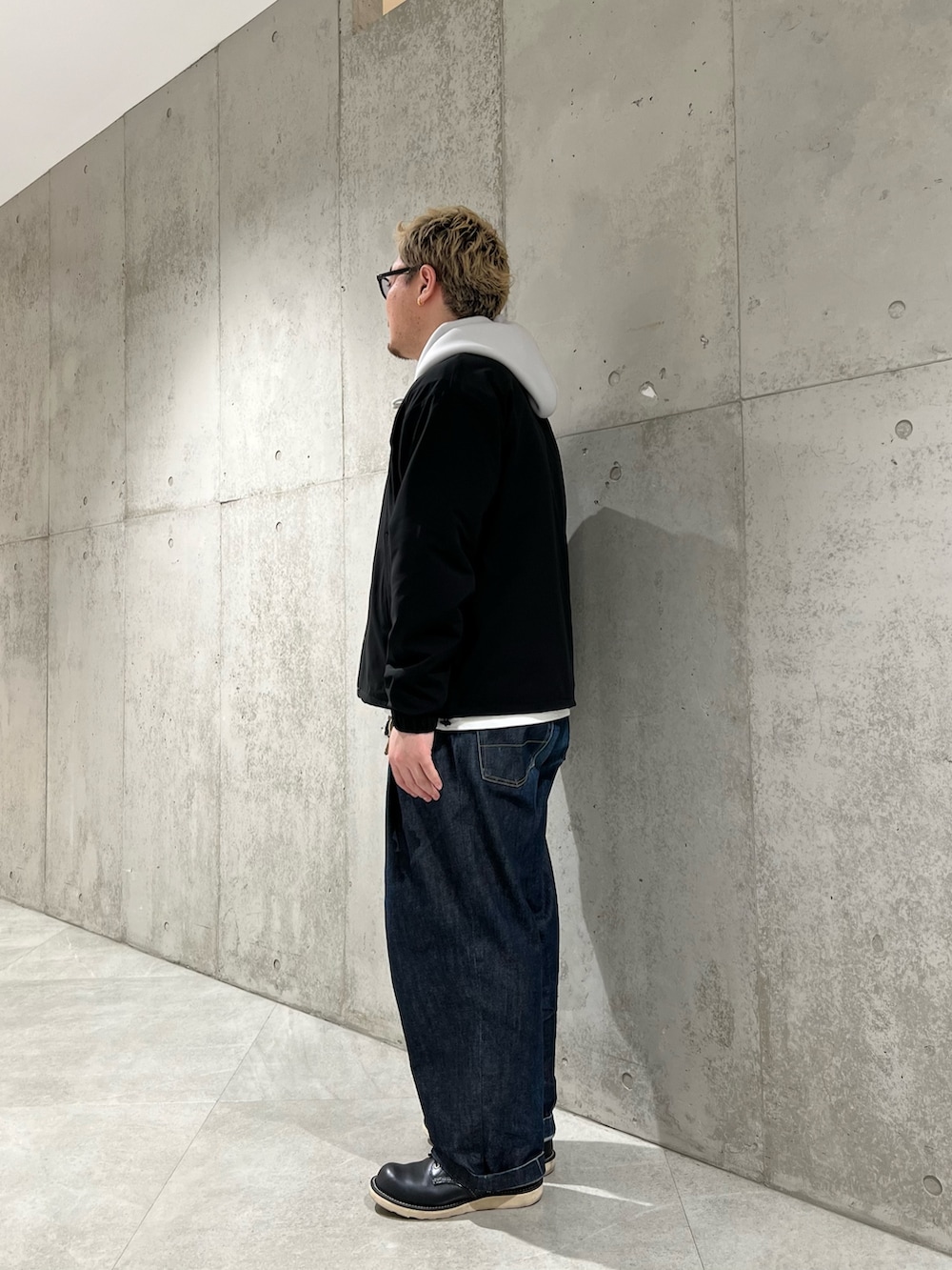 ブラック系のカーディガン/ボレロ、グレー系のパーカー、ブルー系のデニムパンツを着用したメンズの春コーディネートの2枚目の写真