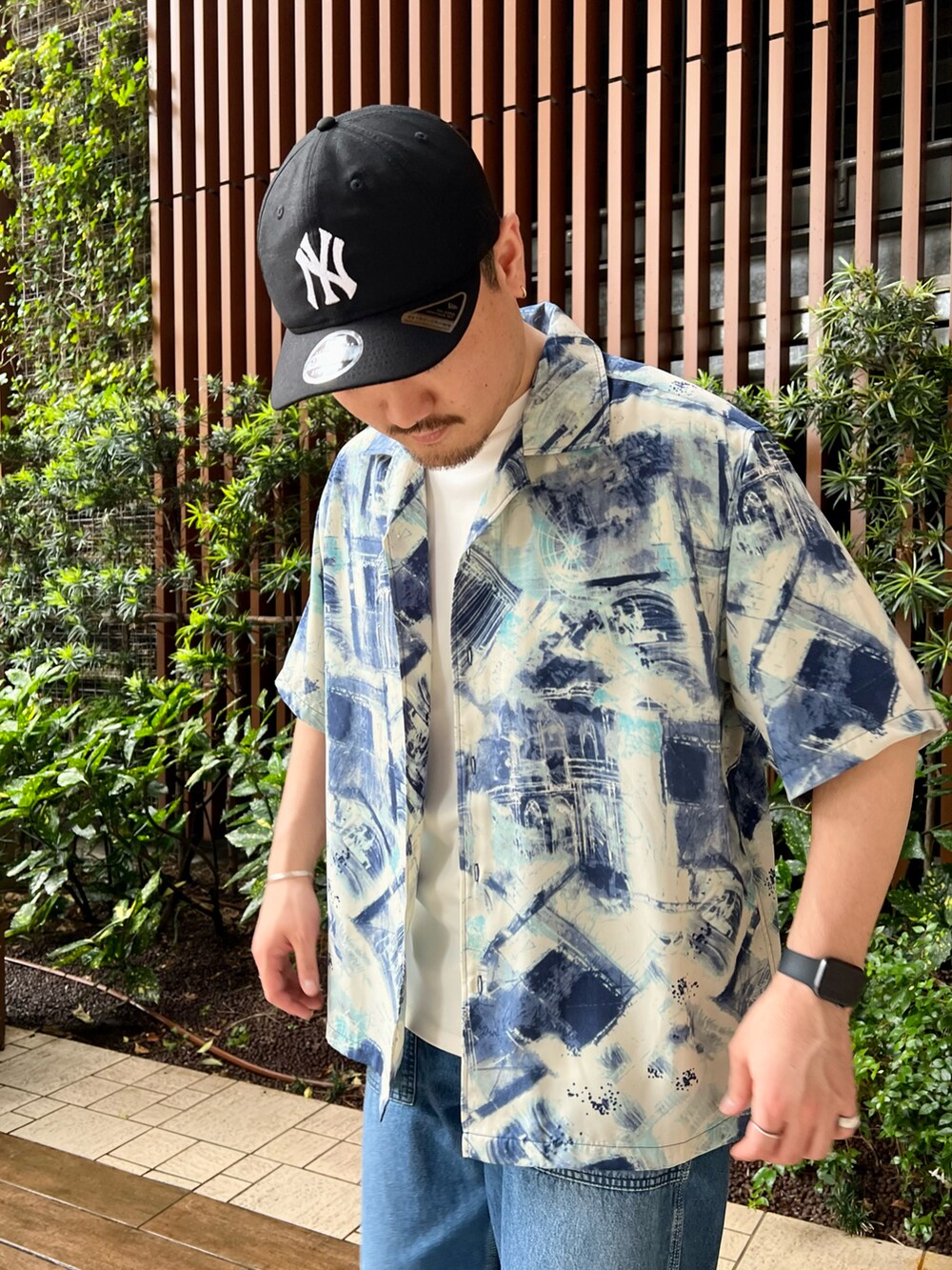 ブルー系のデニムパンツ、ホワイト系のTシャツ/カットソー、グレー系のサンダルを着用したメンズの夏コーディネートの2枚目の写真