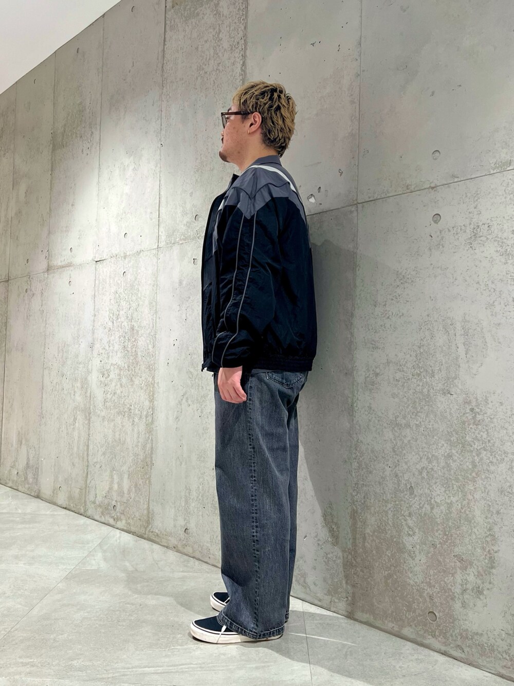 ブラック系のナイロンジャケット、グレー系のTシャツ/カットソー、ブラック系のデニムパンツを着用したメンズの夏コーディネートの2枚目の写真