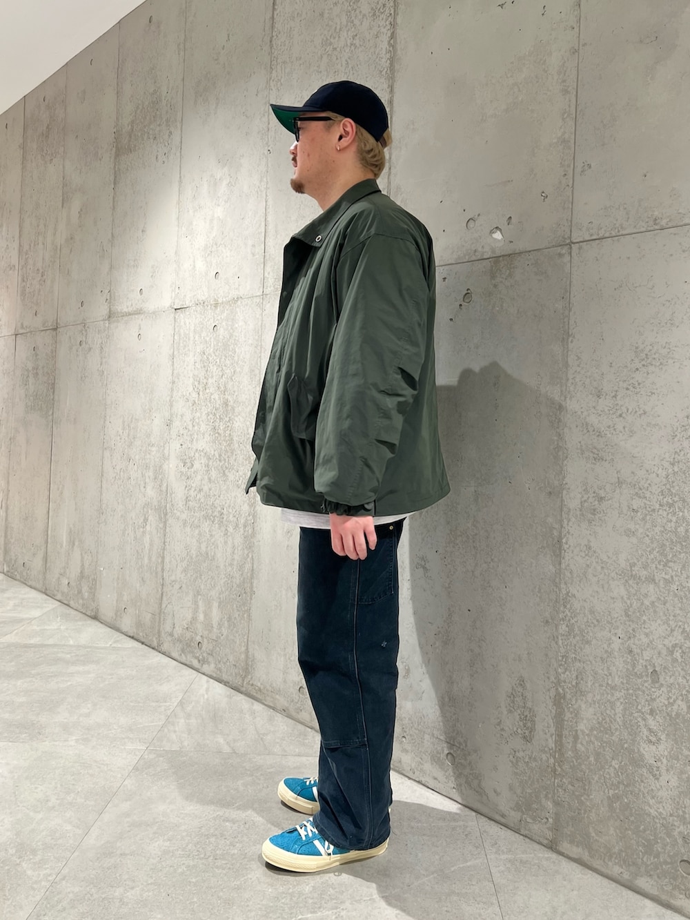 グリーン系のダウンジャケット/コート、ホワイト系のTシャツ/カットソー、ブルー系のスニーカーを着用したメンズの冬コーディネートの2枚目の写真