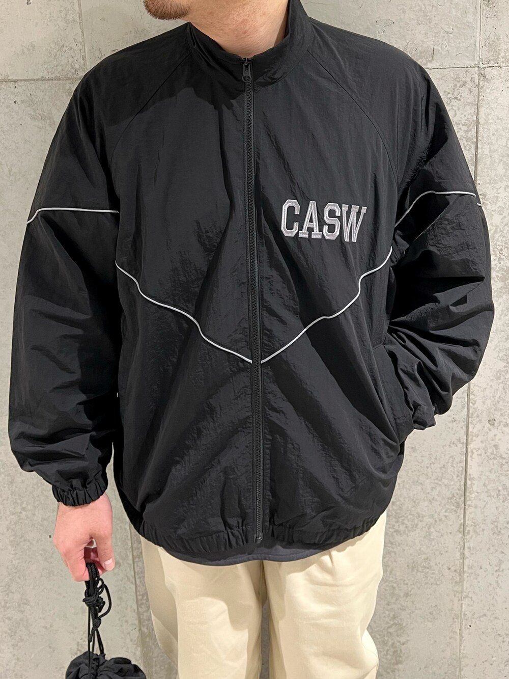 ブラック系のブルゾン、グレー系のTシャツ/カットソー、ホワイト系のチノパンツを着用したメンズの秋コーディネートの4枚目の写真