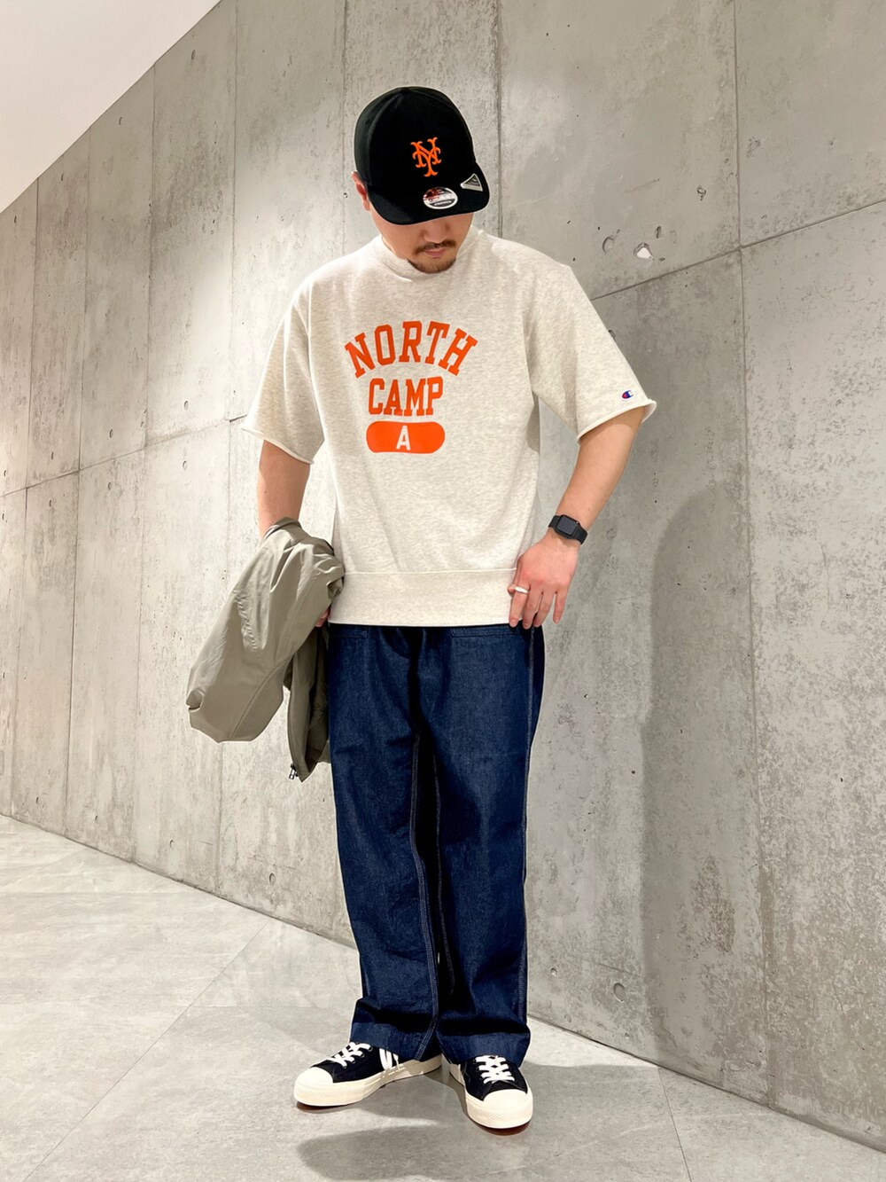 グリーン系のブルゾン、ベージュ系のTシャツ/カットソー、ブルー系のデニムパンツを着用したメンズの春コーディネートの3枚目の写真