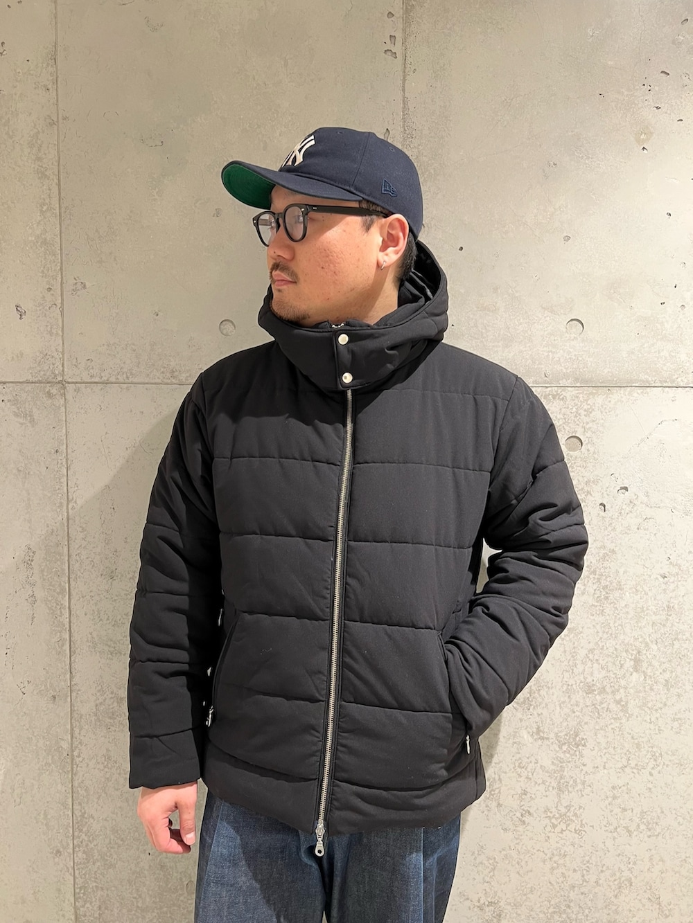 ブラック系のダウンジャケット/コート、ブラック系のTシャツ/カットソー、ホワイト系のスニーカーを着用したメンズの冬コーディネートの4枚目の写真