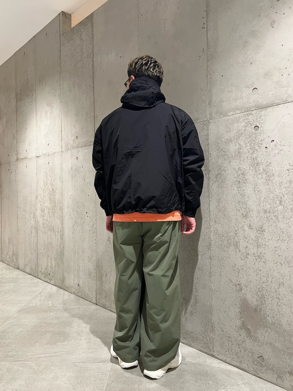ブラック系のマウンテンパーカー、オレンジ系のTシャツ/カットソー、グリーン系のその他パンツを着用したメンズの春コーディネートの3枚目の写真