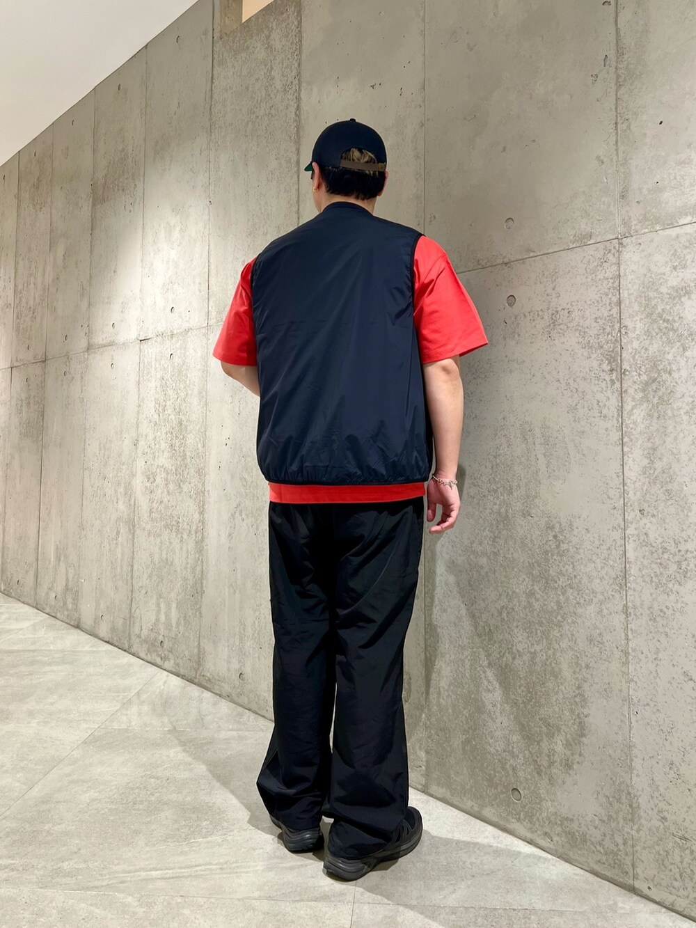 レッド系のTシャツ/カットソー、ブラック系のベスト、ブラック系のその他パンツを着用したメンズの春コーディネートの3枚目の写真