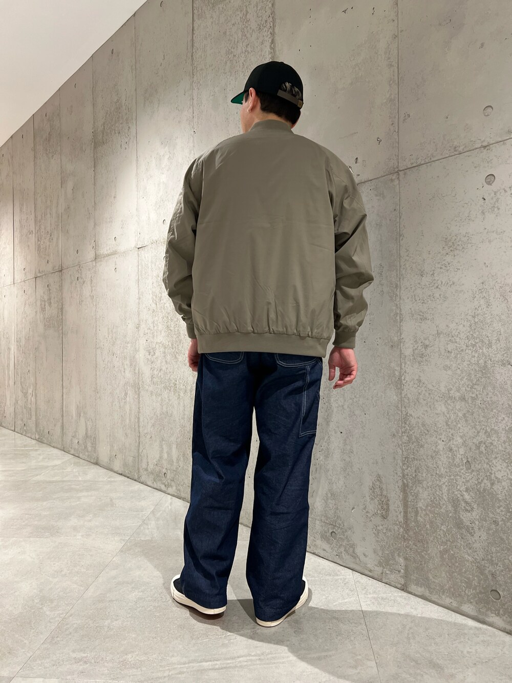 グリーン系のブルゾン、ベージュ系のTシャツ/カットソー、ブルー系のデニムパンツを着用したメンズの春コーディネートの5枚目の写真