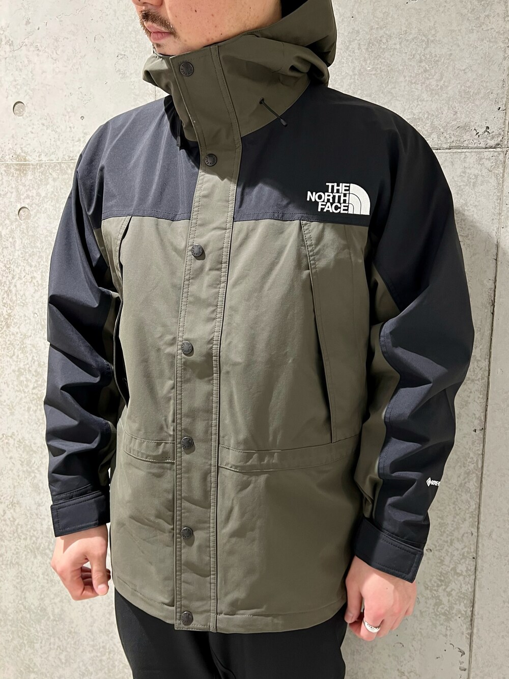 グリーン系のナイロンジャケット、ブラック系のTシャツ/カットソー、ブラック系のその他パンツを着用したメンズの春コーディネートの3枚目の写真