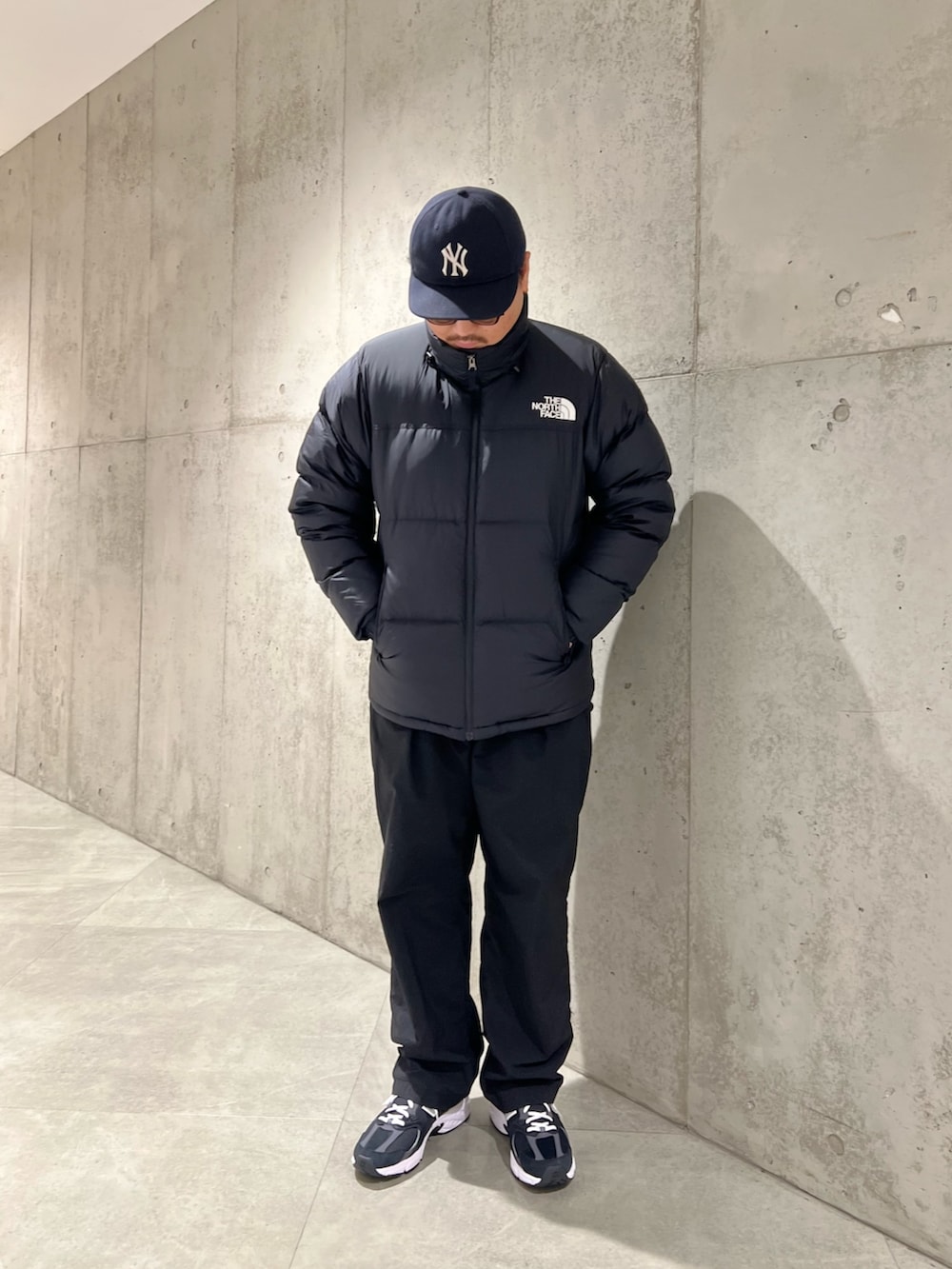 ブラック系のダウンジャケット/コート、ブラック系のパンツ、ブラック系のスニーカーを着用したメンズの秋コーディネートの4枚目の写真