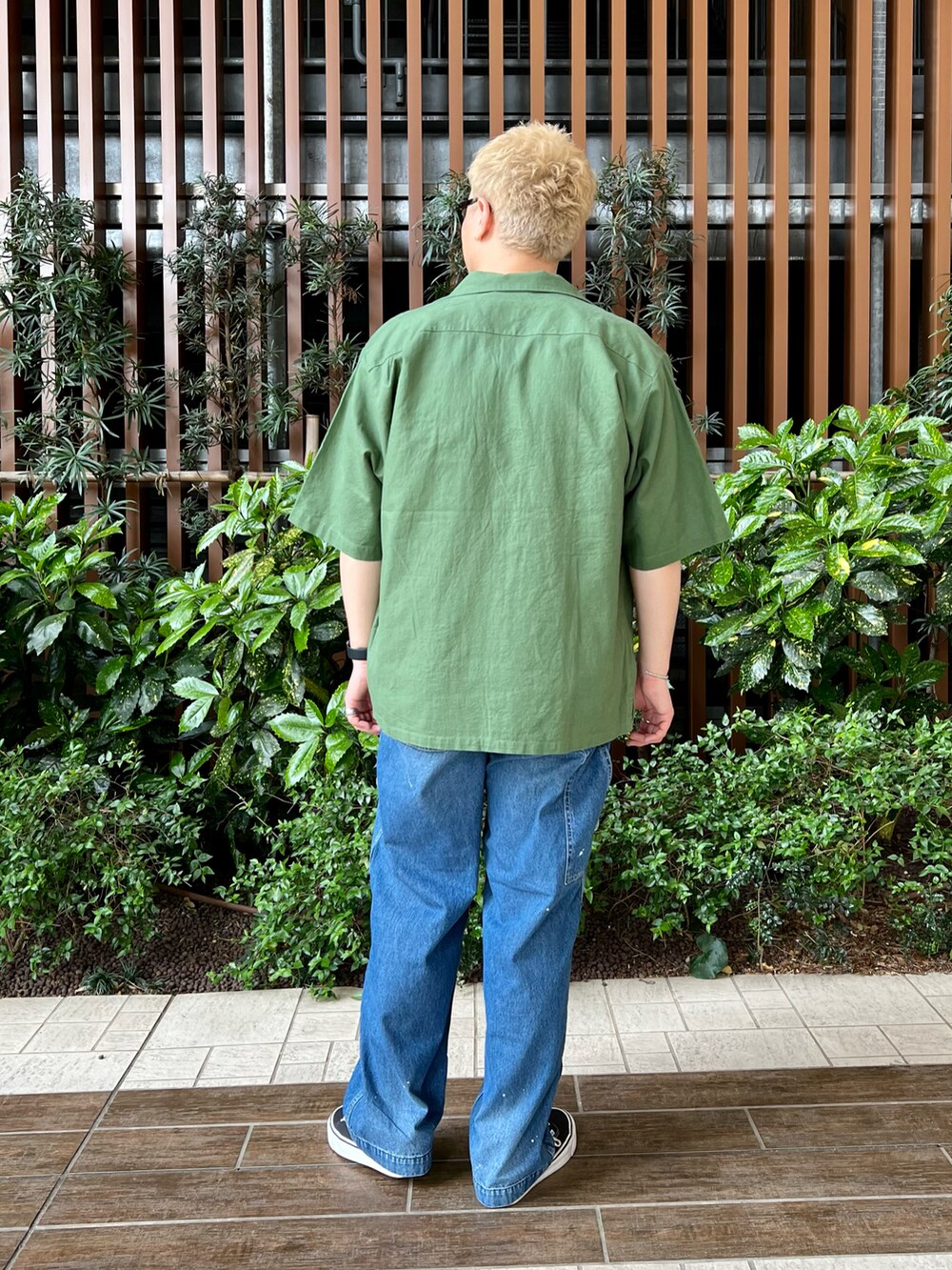 グリーン系のシャツ/ブラウス、ブラック系のスニーカー、ブルー系のデニムパンツを着用したメンズの春コーディネートの4枚目の写真