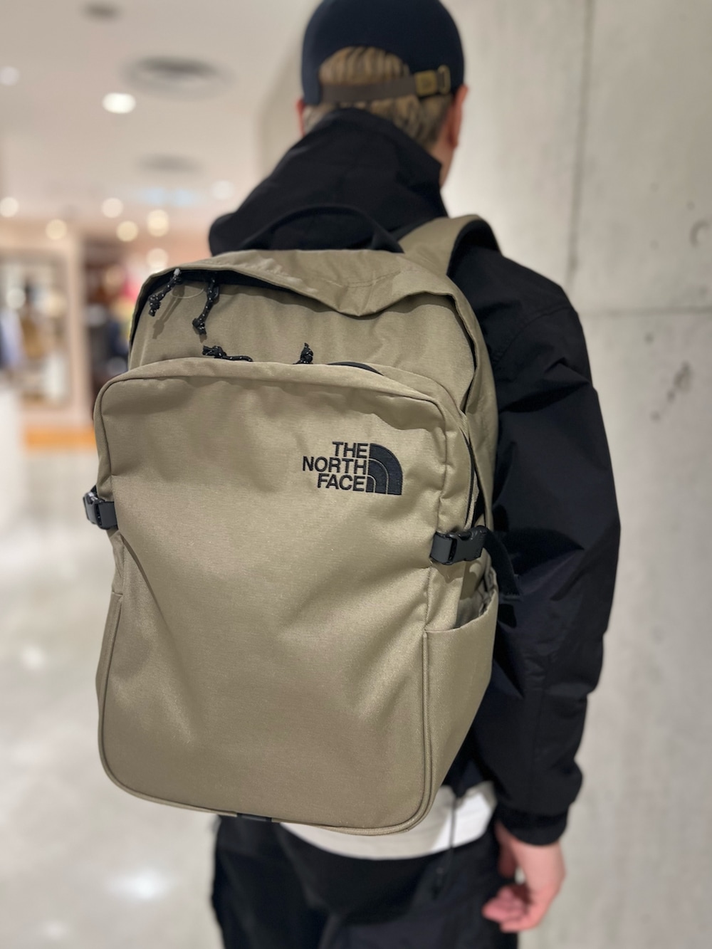 ホワイト系のTシャツ/カットソー、ベージュ系のバックパック/リュック、ブラック系のスニーカーを着用したメンズの春コーディネートの4枚目の写真