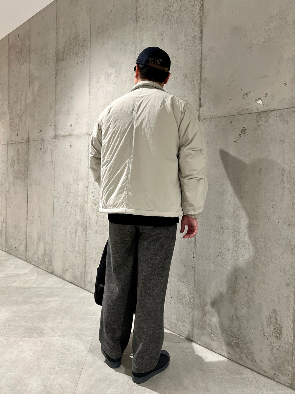 グレー系のナイロンジャケット、ホワイト系のTシャツ/カットソー、ブラック系のニット/セーターを着用したメンズの冬コーディネートの3枚目の写真