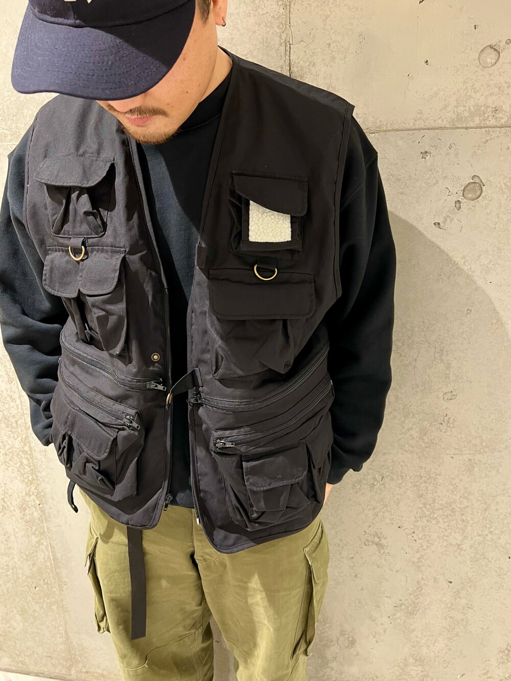 ブラック系のベスト、グリーン系のカーゴパンツ、ブラック系のブーツを着用したメンズの冬コーディネートの2枚目の写真