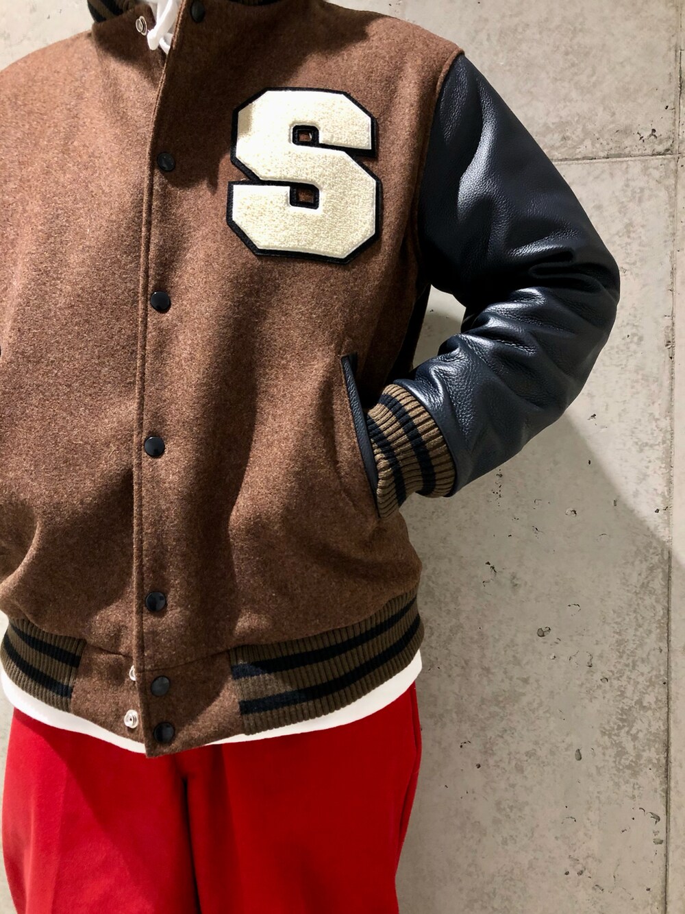 ブラウン系のスタジャン、ホワイト系のパーカー、レッド系のパンツを着用したメンズの秋コーディネートの3枚目の写真