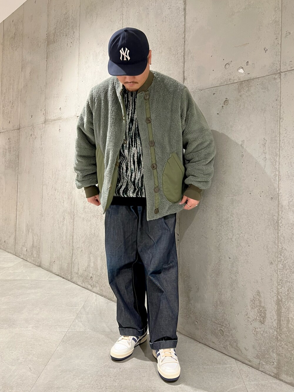 グリーン系のブルゾン、ブルー系のデニムパンツ、ホワイト系のスニーカーを着用したメンズの秋コーディネートの4枚目の写真