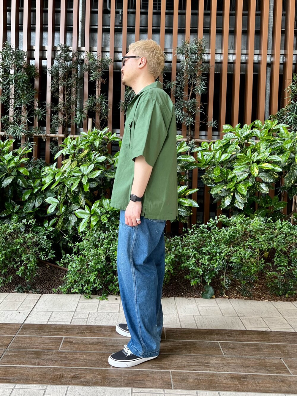 グリーン系のシャツ/ブラウス、ブラック系のスニーカー、ブルー系のデニムパンツを着用したメンズの春コーディネートの3枚目の写真