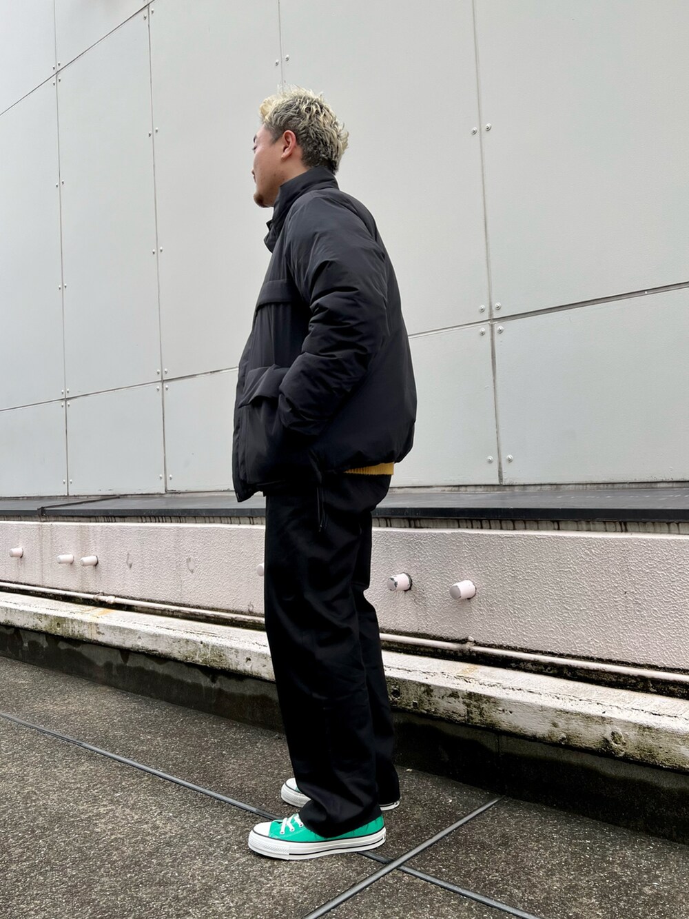 ブラック系のダウンジャケット/コート、イエロー系のカーディガン/ボレロ、ブラック系のチノパンツを着用したメンズの冬コーディネートの4枚目の写真