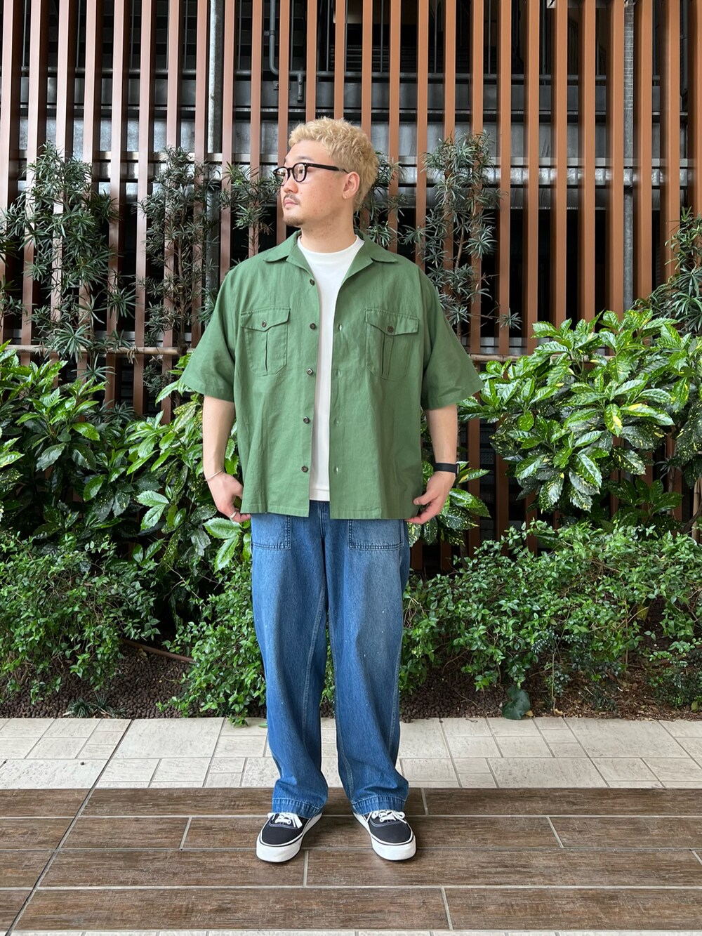 グリーン系のシャツ/ブラウス、ブラック系のスニーカー、ブルー系のデニムパンツを着用したメンズの春コーディネートの2枚目の写真