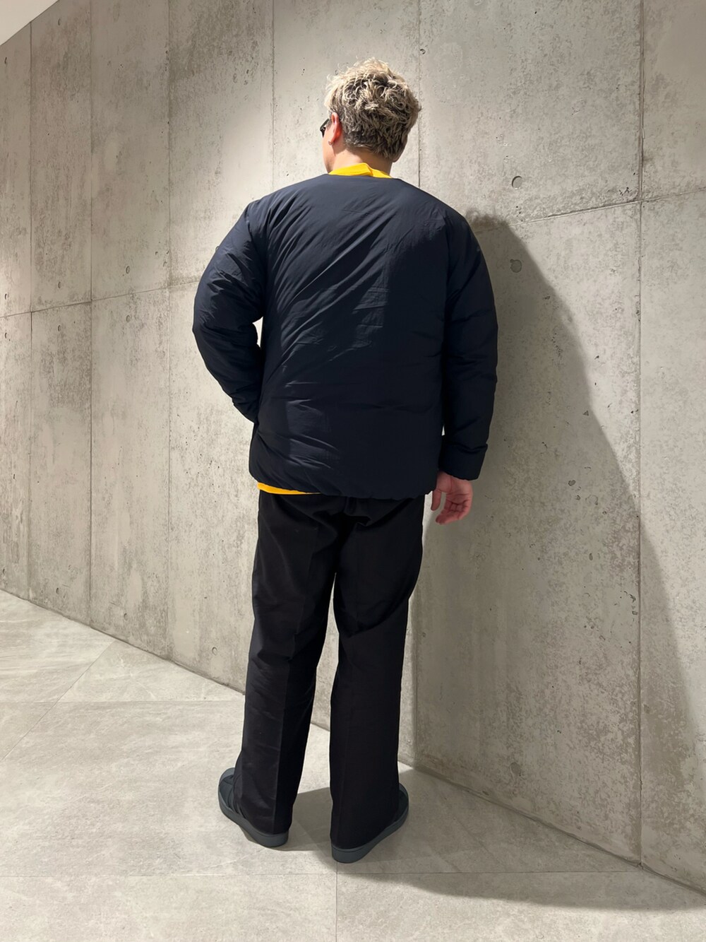 ブラック系のその他パンツ、ブラック系のダウンジャケット/コート、イエロー系のスウェットを着用したメンズの秋コーディネートの3枚目の写真