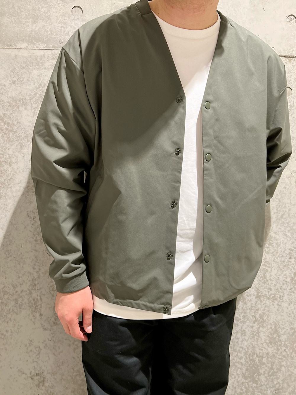 グリーン系のカーディガン/ボレロ、ホワイト系のTシャツ/カットソー、ブラック系のチノパンツを着用したメンズの夏コーディネートの4枚目の写真