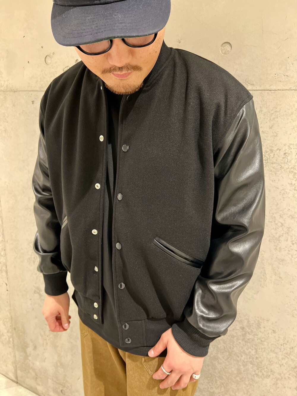 ブラック系のスタジャン、レッド系のスニーカー、ブラウン系のデニムパンツを着用したメンズの秋コーディネートの4枚目の写真