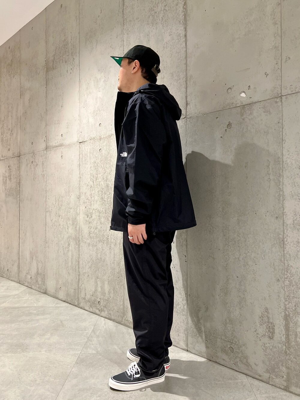 ブラック系のマウンテンパーカー、ホワイト系のTシャツ/カットソー、ブラック系のスニーカーを着用したメンズの春コーディネートの4枚目の写真