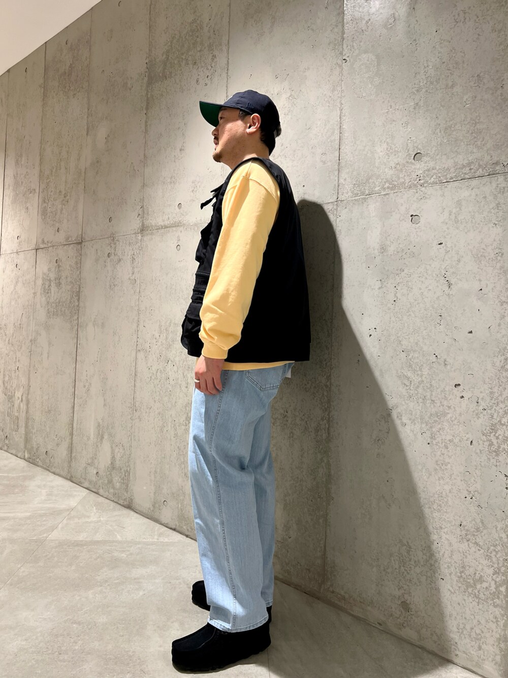 ブラック系のベスト、ブルー系のデニムパンツ、ブラック系のブーツを着用したメンズの春コーディネートの3枚目の写真