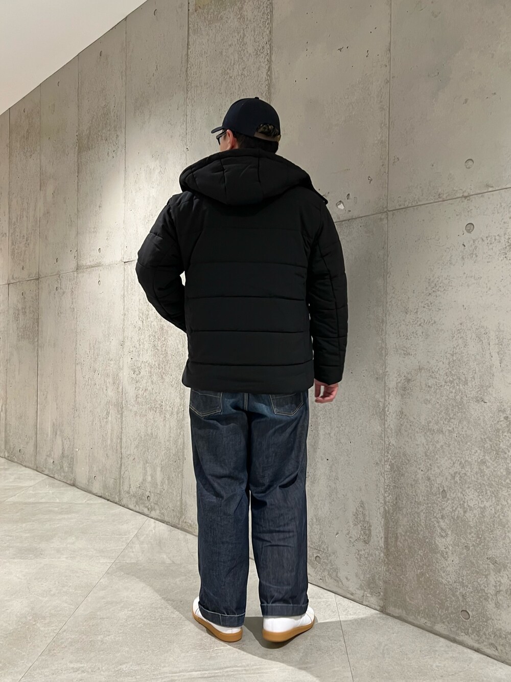 ブラック系のダウンジャケット/コート、ブラック系のTシャツ/カットソー、ホワイト系のスニーカーを着用したメンズの冬コーディネートの3枚目の写真