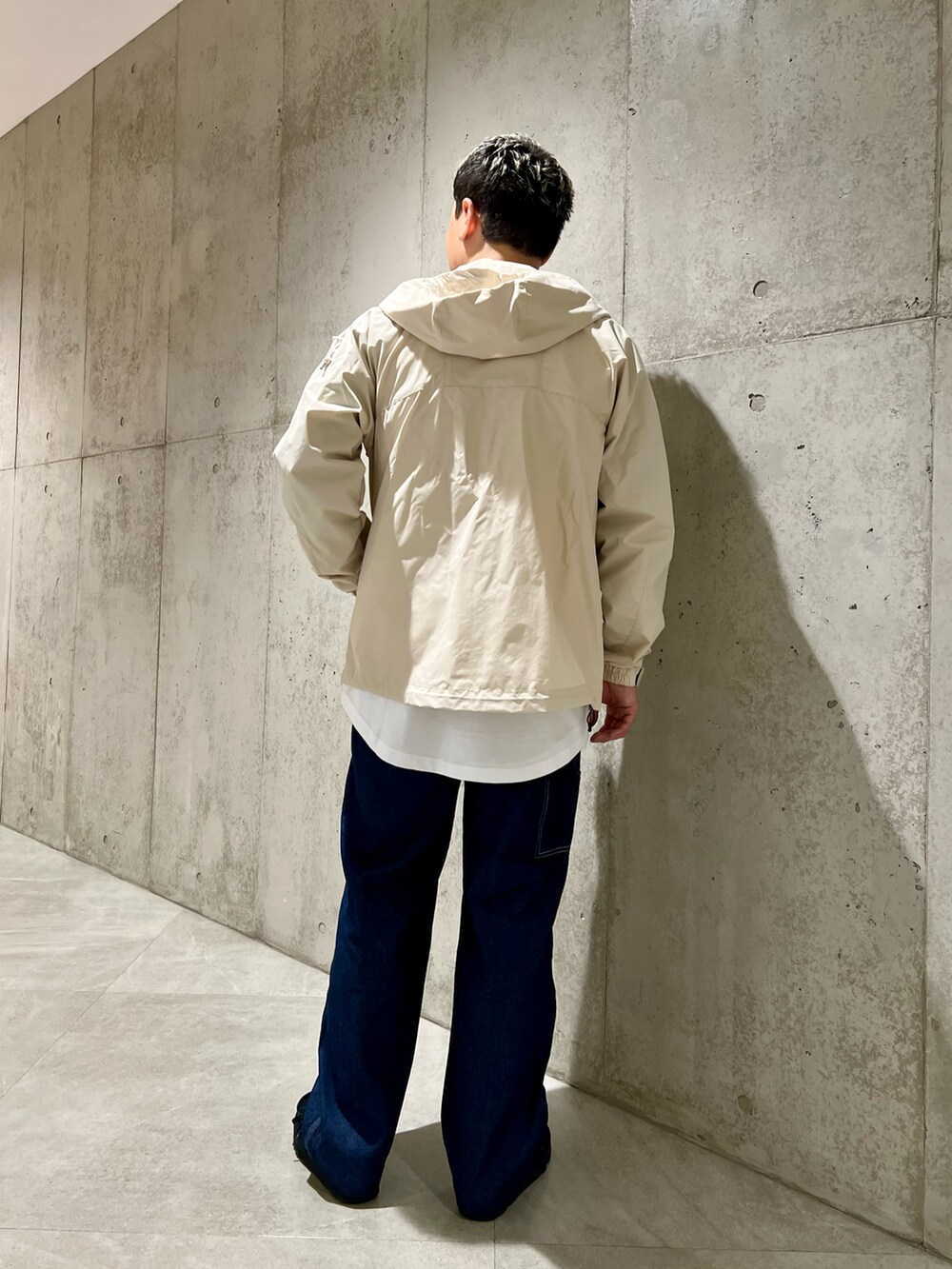 ホワイト系のマウンテンパーカー、グリーン系のTシャツ/カットソー、ブラック系のブーツを着用したメンズの春コーディネートの4枚目の写真