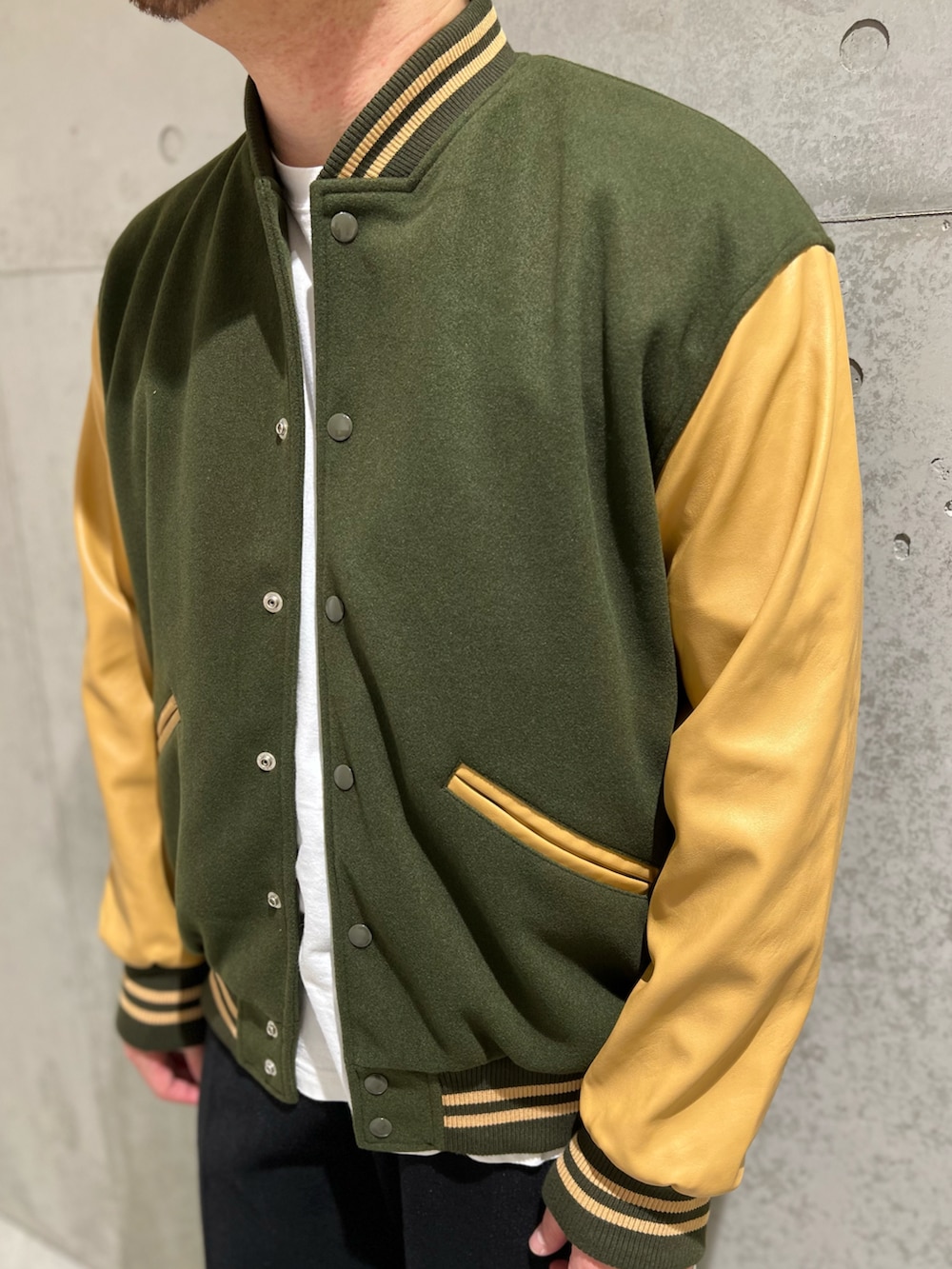 グリーン系のスタジャン、ホワイト系のTシャツ/カットソー、ブラック系のその他パンツを着用したメンズの秋コーディネートの2枚目の写真