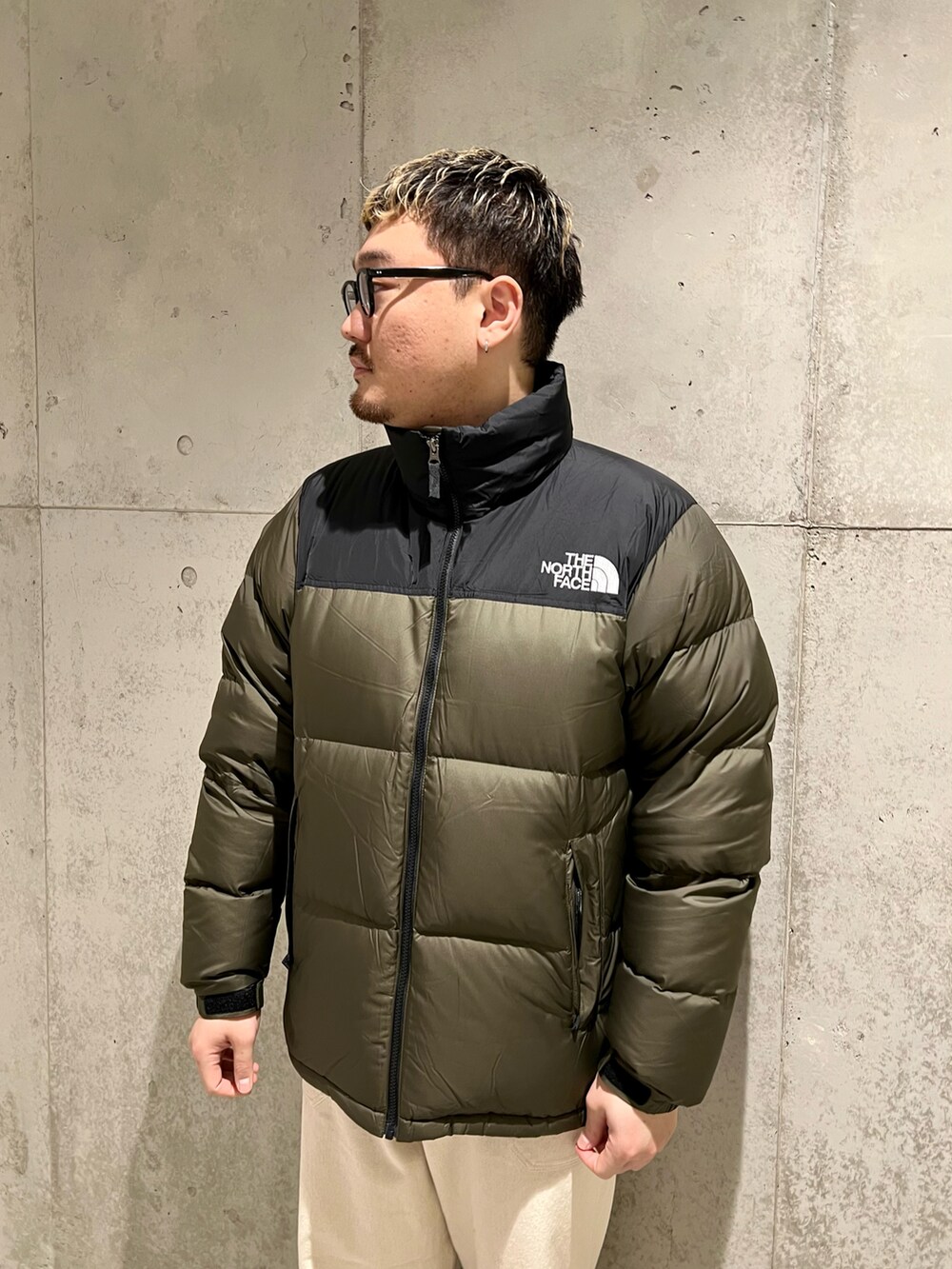 グリーン系のダウンジャケット/コート、レッド系のモカシン/デッキシューズ、ホワイト系のパンツを着用したメンズの冬コーディネートの4枚目の写真