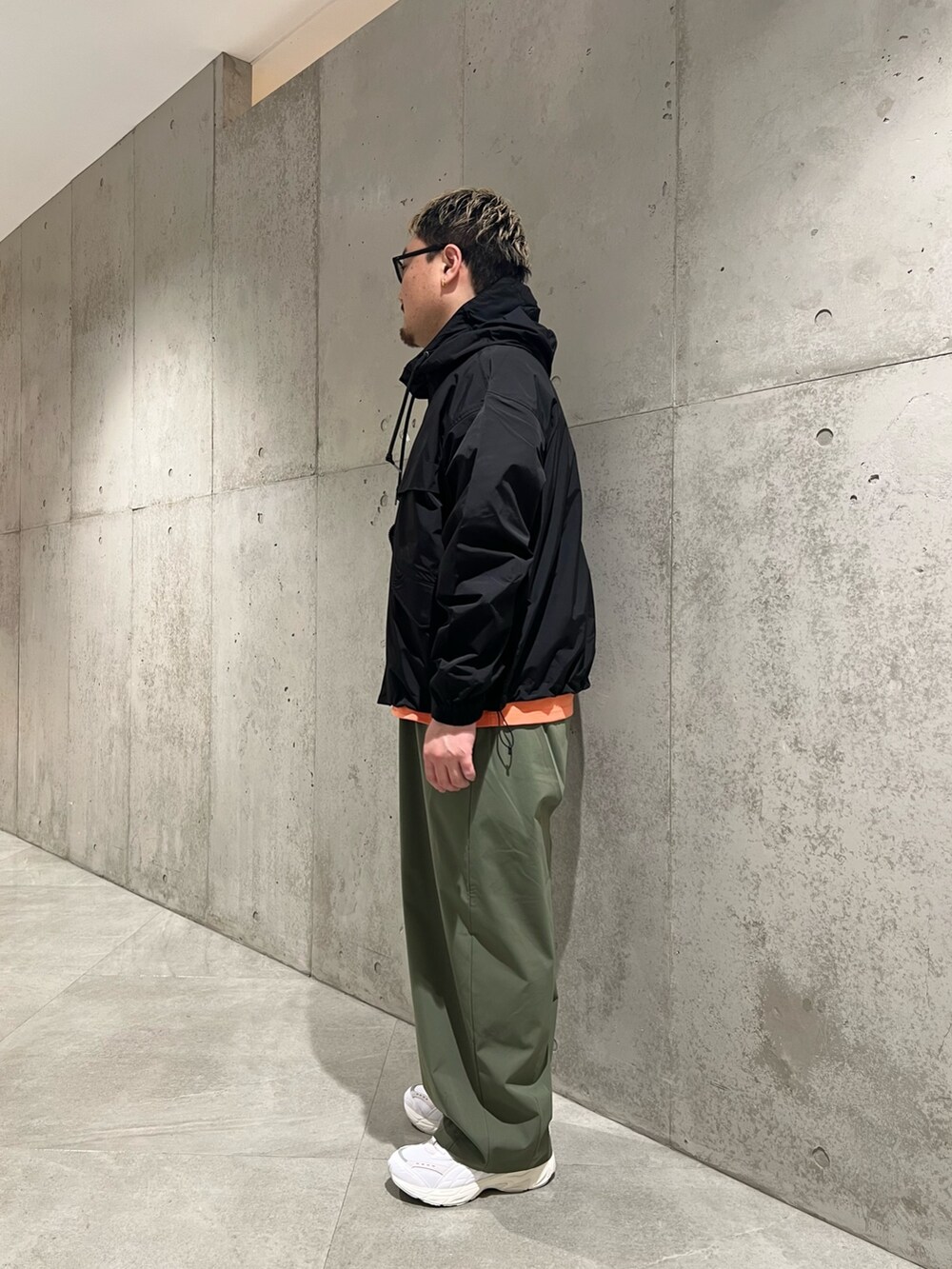 ブラック系のマウンテンパーカー、オレンジ系のTシャツ/カットソー、グリーン系のその他パンツを着用したメンズの春コーディネートの2枚目の写真
