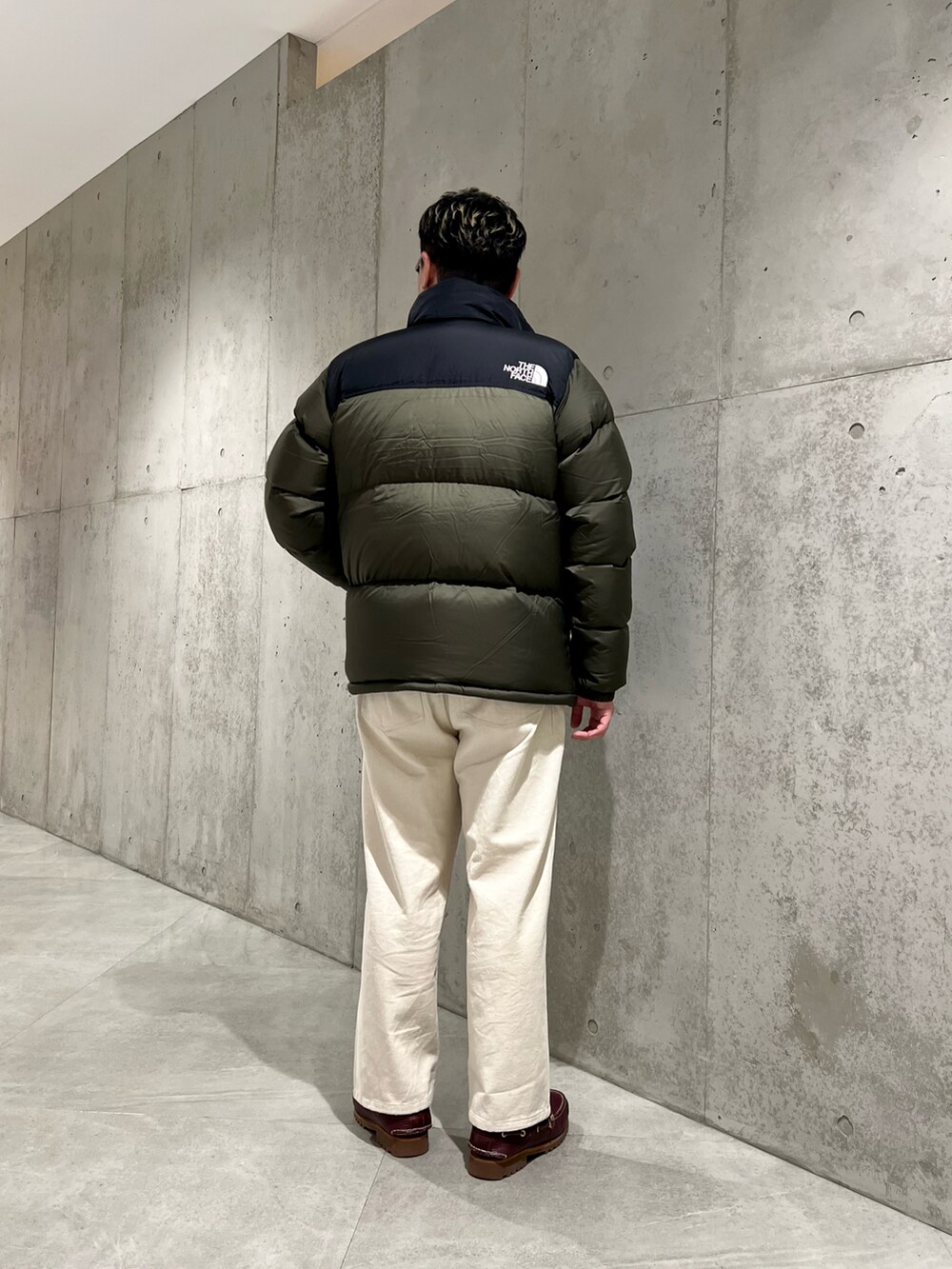 グリーン系のダウンジャケット/コート、レッド系のモカシン/デッキシューズ、ホワイト系のパンツを着用したメンズの冬コーディネートの3枚目の写真