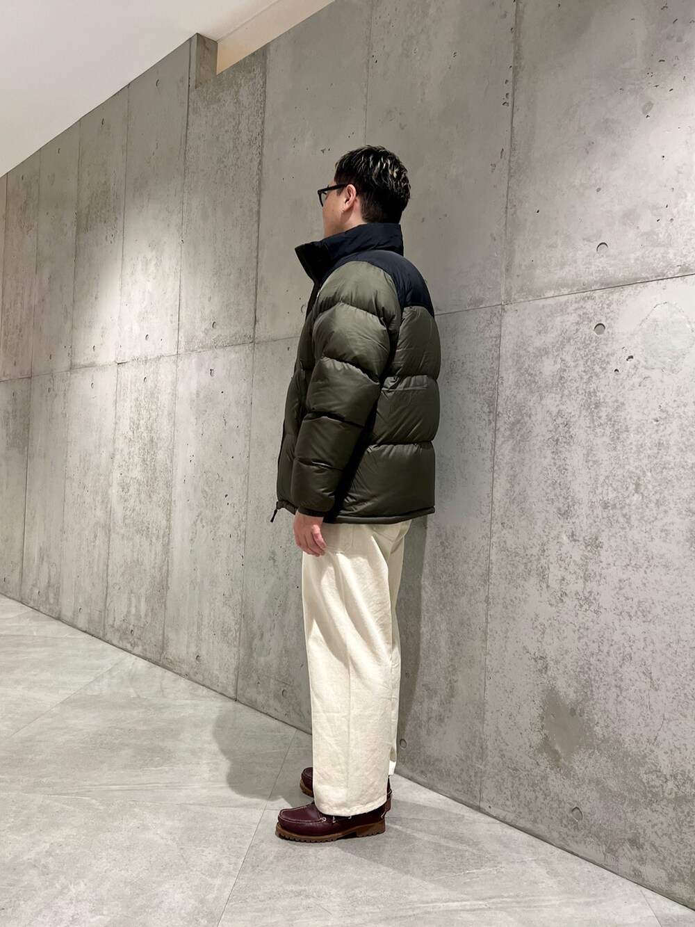 グリーン系のダウンジャケット/コート、レッド系のモカシン/デッキシューズ、ホワイト系のパンツを着用したメンズの冬コーディネートの2枚目の写真
