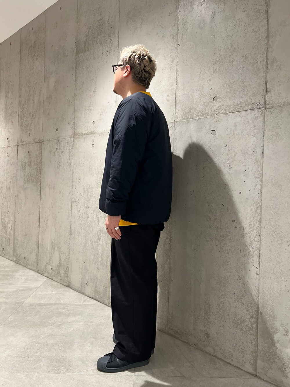 ブラック系のその他パンツ、ブラック系のダウンジャケット/コート、イエロー系のスウェットを着用したメンズの秋コーディネートの2枚目の写真