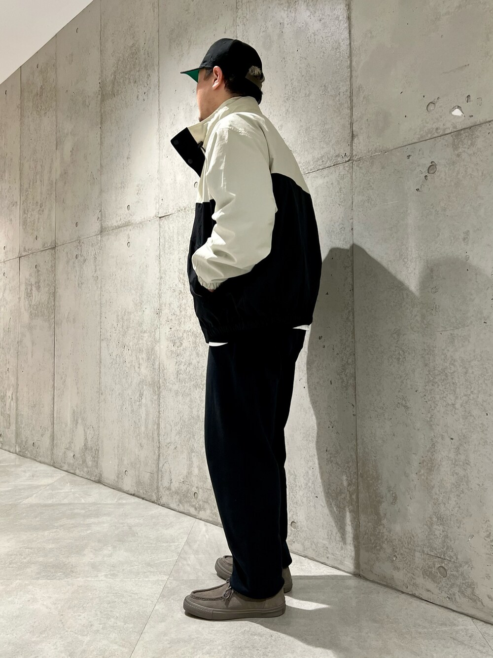 ブラック系のナイロンジャケット、ベージュ系のスニーカー、ブラック系のスウェットを着用したメンズの春コーディネートの3枚目の写真