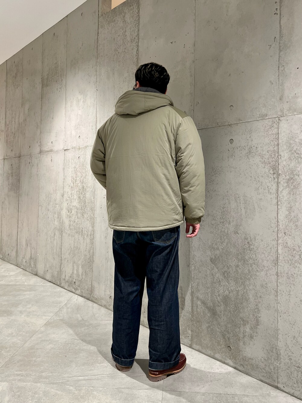 グリーン系のブルゾン、レッド系のモカシン/デッキシューズ、イエロー系のカーディガン/ボレロを着用したメンズの冬コーディネートの3枚目の写真