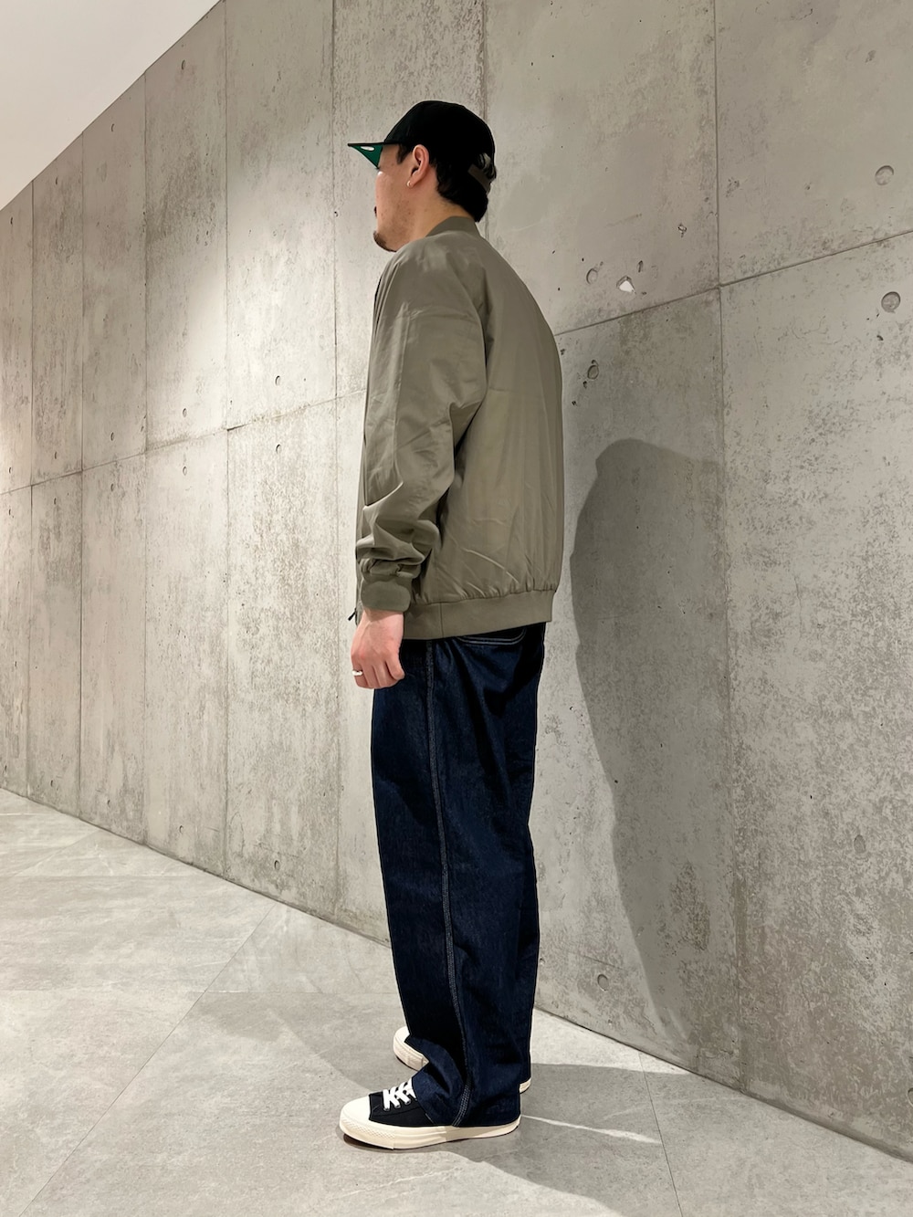 グリーン系のブルゾン、ベージュ系のTシャツ/カットソー、ブルー系のデニムパンツを着用したメンズの春コーディネートの4枚目の写真