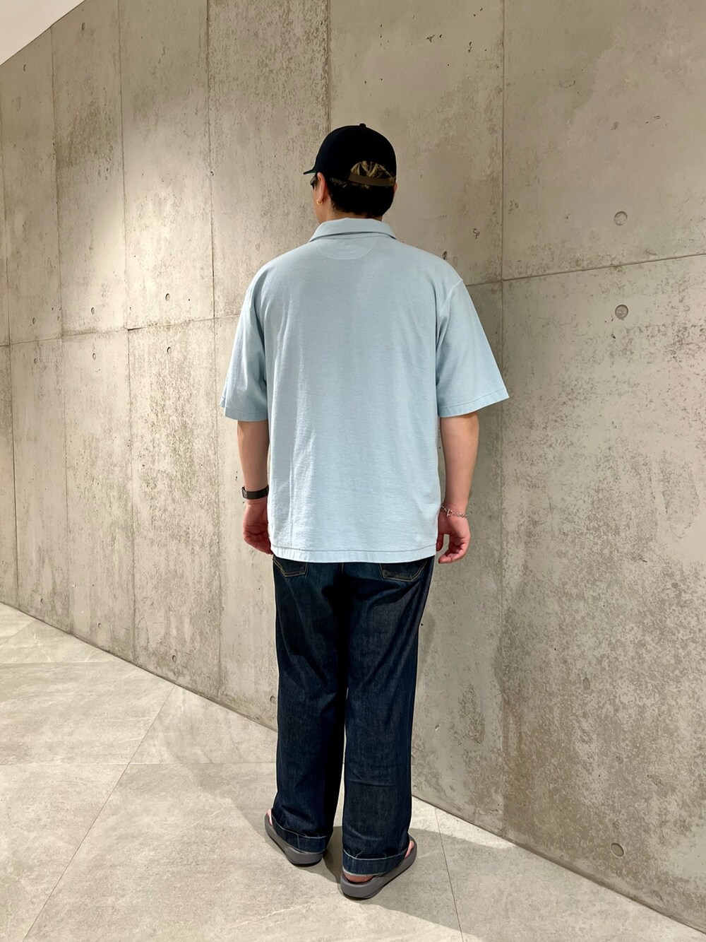 ブルー系のポロシャツ、ブルー系のデニムパンツ、グレー系のサンダルを着用したメンズの春コーディネートの3枚目の写真