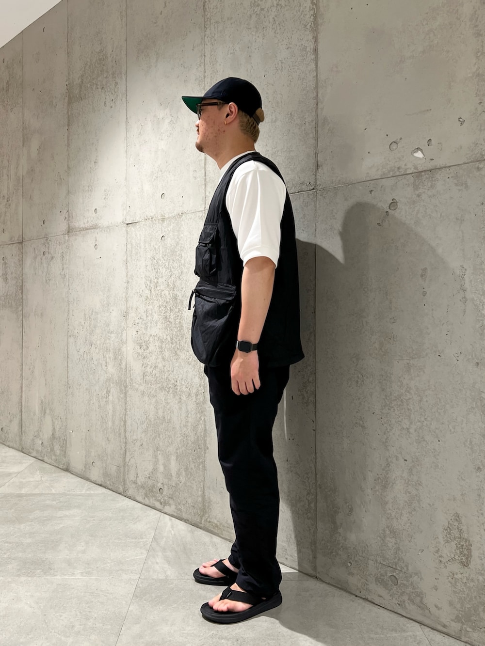 ホワイト系のTシャツ/カットソー、ブラック系のベスト、ブラック系のサンダルを着用したメンズの夏コーディネートの3枚目の写真